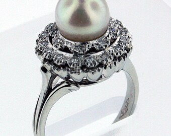 May include: A silver ring with a large white pearl set in a halo of small diamonds.