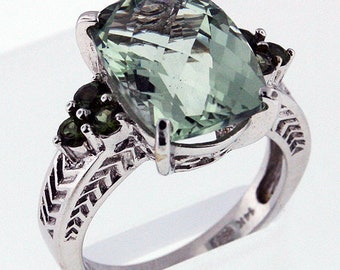 May include: A silver ring with a large, green, cushion-cut gemstone surrounded by smaller green gemstones.