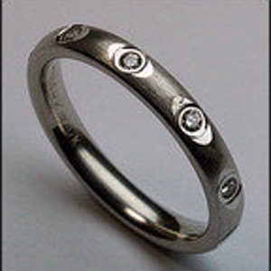 May include: A silver wedding band with four small diamonds set in the band.