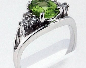 May include: A silver ring with a large oval green gemstone surrounded by smaller white gemstones.