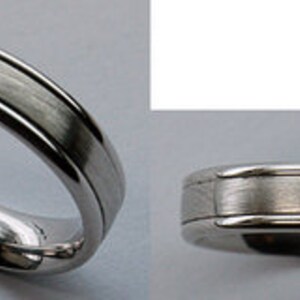 May include: A silver-colored ring with a brushed metal center band and polished edges. The ring has a simple, elegant design, suitable for everyday wear or special occasions. The ring is shown from two different angles.