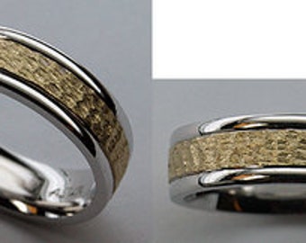 May include: A silver and gold wedding band with a textured gold band.