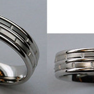 May include: A silver wedding band with a textured design of three rows of rectangular shapes.