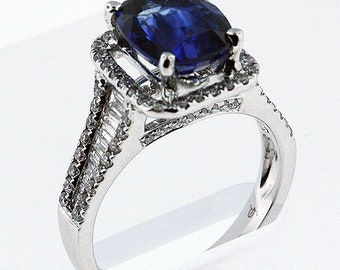 May include: A silver ring with a large, cushion-cut sapphire surrounded by a halo of smaller diamonds. The band is set with baguette-cut diamonds.
