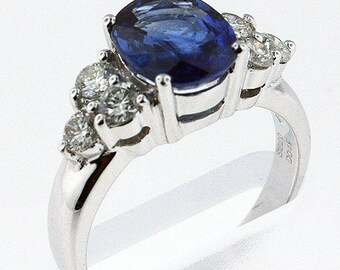 May include: A silver ring with a large oval blue sapphire and smaller diamonds set around it.