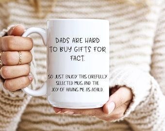 May include: White ceramic mug with black text that reads "DADS ARE HARD TO BUY GIFTS FOR, FACT. SO JUST ENJOY THIS CAREFULLY SELECTED MUG AND THE JOY OF HAVING ME AS A CHILD."
