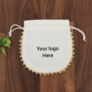May include: White drawstring bag with gold trim and the text "Your logo Here" printed on the front.
