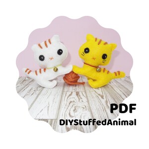 May include: A PDF pattern for sewing two felt cat toys. The cats are white and yellow with orange stripes and are holding a ball of yarn. The pattern is from DIYStuffedAnimal.
