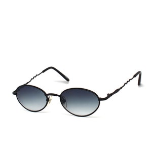 Puede incluir: Gafas de sol ovaladas negras con un fino marco de metal y lentes gris oscuro.