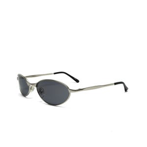 May include: Silver-framed sunglasses with oval, dark gray lenses. The sunglasses have a sleek, modern design with thin temples and black earpieces. The overall aesthetic is minimalist and stylish, suitable for various fashion styles.