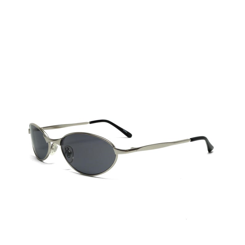 May include: Silver-framed sunglasses with oval, dark gray lenses. The sunglasses have a sleek, modern design with thin temples and black earpieces. The overall aesthetic is minimalist and stylish, suitable for various fashion styles.