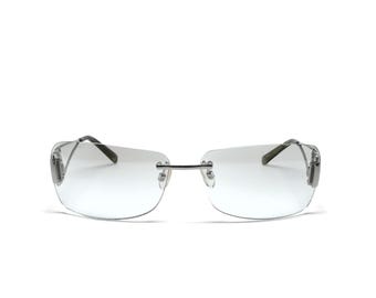 May include: Silver frame sunglasses with clear lenses. The sunglasses have a rectangular shape and a thin metal frame.