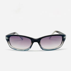Puede incluir: Un par de gafas de sol negras y grises con lentes degradados. Las gafas tienen una forma rectangular y un marco delgado.