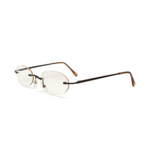 May include: Rimless oval eyeglasses with a dark brown metal frame and temples. The lenses are clear, and the nose bridge is a light brown metal. The glasses are designed for a minimalist aesthetic.