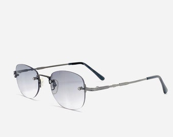 May include: A pair of rimless sunglasses with a silver frame and gray lenses. The sunglasses have a subtle design detail on the arms.