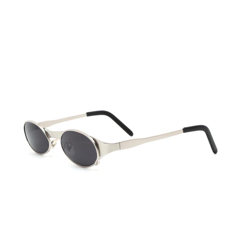 Puede incluir: Gafas de sol ovaladas plateadas con lentes negros y patillas de goma negra.