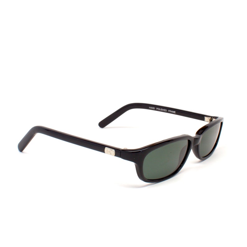 May include: Black sunglasses with a dark green lens and a black frame. The frame is labeled "HAND POLISHED FRAME".