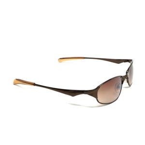 K&ouml;nnte beinhalten: Braune Sonnenbrille mit Metallrahmen und braunen Verlaufsgl&auml;sern. Die Sonnenbrille hat einen d&uuml;nnen Metallrahmen und ein geschwungenes Design.