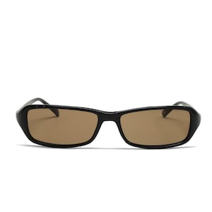 May include: Black rectangular sunglasses with brown tinted lenses. The sunglasses have a sleek, modern design, with a thick black frame and a slightly curved shape. The lenses are a warm brown color, providing a contrast to the black frame.