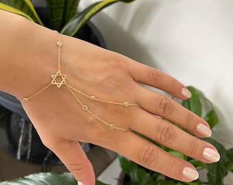 May include: A gold chain bracelet with a star of David charm and small clear stones. The bracelet is designed to be worn on the wrist and finger.