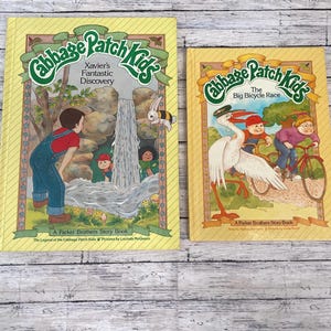 Könnte beinhalten: Zwei Vintage-Bücher der Cabbage Patch Kids. Das erste Buch, "Xavier's Fantastic Discovery", zeigt einen Jungen in Latzhosen. Das zweite Buch, "The Big Bicycle Race", zeigt Kinder auf Fahrrädern. Beide Bücher haben gelbe Einbände.