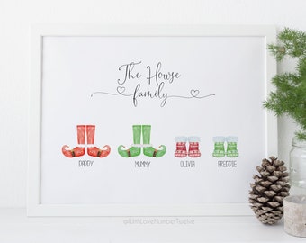 May include: A white framed print with the text "The House family" and four pairs of elf shoes in red, green, and red and white. The shoes are labeled "Daddy", "Mummy", "Olivia", and "Freddie".