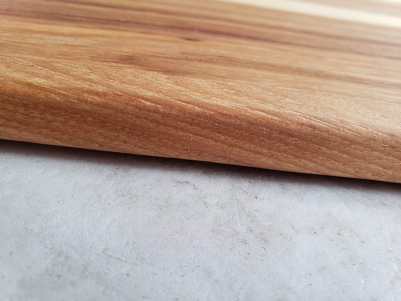 Puede incluir: Primer plano de una superficie de madera marr&oacute;n claro con un borde liso ligeramente redondeado. La superficie tiene un patr&oacute;n de veta de madera natural.