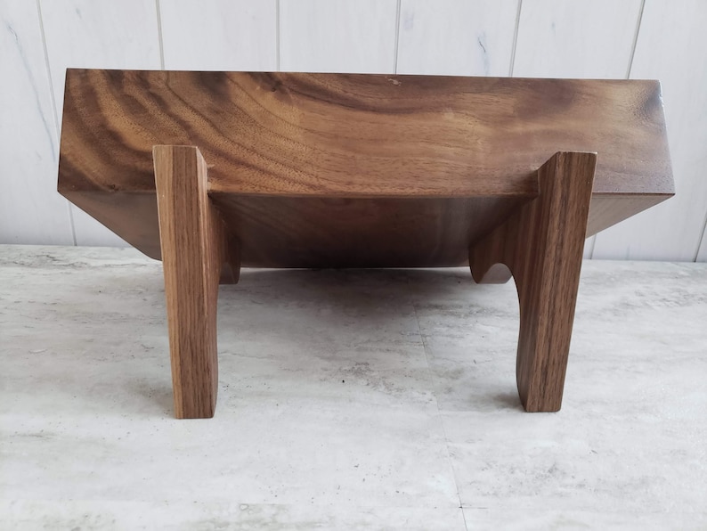 Puede incluir: Una bandeja de servir de madera con un acabado de madera natural y cuatro patas. La bandeja est&aacute; hecha de madera maciza y tiene una forma rectangular.