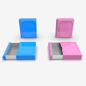 Puede incluir: Un conjunto de dos cajas con forma de libro, una azul y otra rosa, con un caj&oacute;n que se desliza hacia afuera. Las cajas tienen un marco decorativo en la parte delantera y est&aacute;n sobre un fondo blanco.