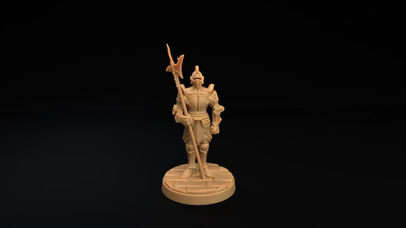 Op de afbeelding: Een miniatuurfiguur van een ridder in volledige bepantsering, die een speer met een scherpe punt vasthoudt. De ridder staat op een ronde basis met een steenachtige textuur.