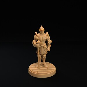 Op de afbeelding: Een miniatuur plastic figuur van een ridder in volledige bepantsering, die een zwaard vasthoudt. De ridder staat op een ronde basis met een steenachtige textuur.