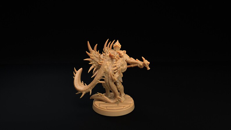 Op de afbeelding: Een gedetailleerd miniatuurbeeldje van een wezen met een stekelige staart en vleugels, dat een harnas draagt en een wapen vasthoudt. Het beeldje is in een lichtbruine kleur geverfd en staat op een ronde basis.