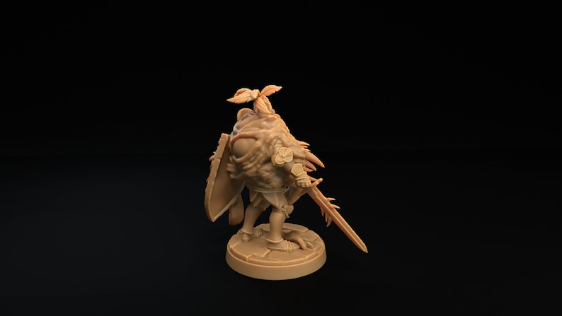 Op de afbeelding: Een miniatuurfiguur van een ridder, geschilderd in een lichtbruine kleur. De ridder draagt ​​een harnas en houdt een zwaard en schild vast. De ridder heeft een groot, enkel oog en een kroon van bladeren op zijn hoofd.
