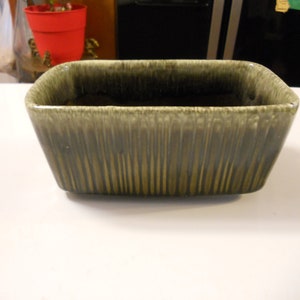 May include: A rectangular green ceramic planter with a textured, striped design. The planter is empty.