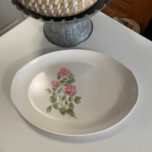 May include: White oval serving platter with a floral design featuring pink roses and green leaves.