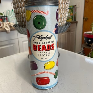 May include: Vintage Playskool Jumbo-Assorted Beads in a metal container. The container is decorated with colorful beads and the text "Playskool Jumbo-Assorted Beads 5 Shapes 6 Colors 2 Strings No. 702".