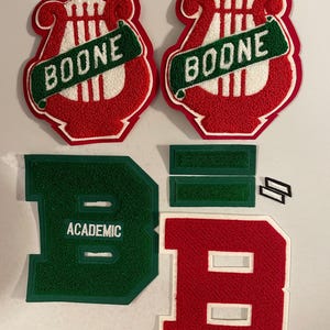 May include: Set of red and green felt patches with the word "BOONE" and a harp design. The patches are for a school or organization. There are also two green felt patches with the word "ACADEMIC" and two red felt patches shaped like the letter "B".