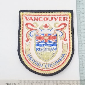 May include: A red, white, and blue embroidered patch with the words "Vancouver, British Columbia" and a crest featuring a maple leaf and a shield with the Union Jack. The patch is approximately 2 inches wide.