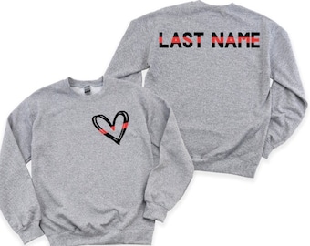May include: Gray sweatshirt with a black heart with a red stripe on the front and the text "LAST NAME" in black with a red stripe on the back.