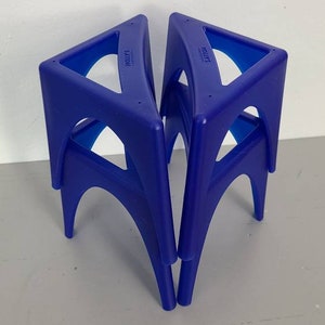 May include: Three blue plastic triangular stools stacked on top of each other. The stools are made by the company "Little" and "Step2".