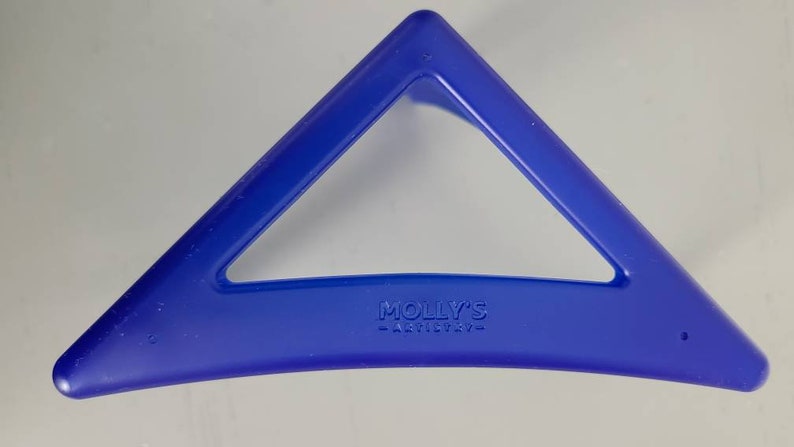 May include: A blue plastic triangle-shaped hair clip with the text "MOLLY'S -ARTISTRY- " embossed on the bottom.