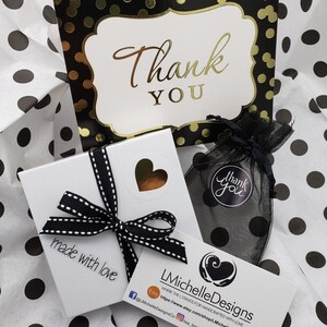May include: A white gift box with a black and white ribbon, a black and white thank you card with gold polka dots, and a black and white thank you bag. The gift box has a sticker that says "made with love". The card has the text "Thank You". The bag has the text "Thank You".