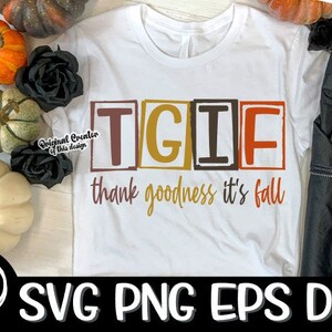 May include: A white t-shirt featuring the text "TGIF thank goodness it's fall" in a retro font. The letters are enclosed in boxes with autumnal colours. The shirt is displayed on a white surface with autumnal decorations.