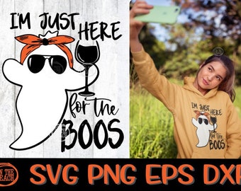 May include: A white ghost illustration with sunglasses and an orange bandana holding a wine glass, with the text "I'M JUST HERE for the BOOS". A person is wearing a mustard yellow hoodie with the same graphic.