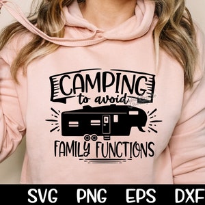 May include: A pink hoodie with the text "Camping to avoid family functions" and a black silhouette of a camper trailer.