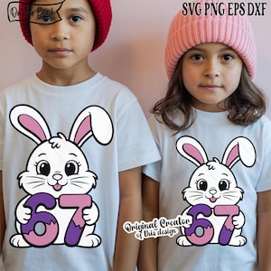 Pode incluir: Duas crianças vestindo camisetas brancas com um coelho de desenho animado segurando o número 67 em roxo e rosa. O coelho tem orelhas rosas e está sorrindo. Uma criança usa um gorro vermelho, a outra um gorro rosa. O texto na parte superior diz "SVG PNG EPS DXF".