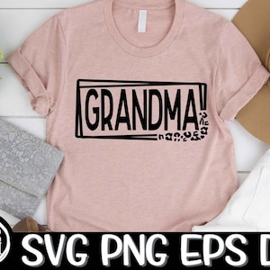 May include: A pink t-shirt with the text "Grandma!" in a black rectangle with a black leopard print design below. The text is in a bold, blocky font.