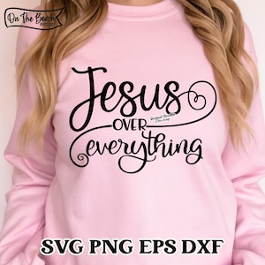 May include: Pink sweatshirt with the text "Jesus over everything" in black cursive lettering. The text is surrounded by a decorative heart shape.
