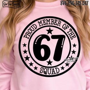 May include: A light pink sweatshirt with a black circular design. The design reads "PROUD MEMBER OF THE 67 SQUAD" with stars and text. The top left corner has the text "On The Beach Boutique".