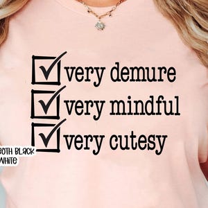Pode incluir: Uma camiseta rosa com uma lista de verifica&ccedil;&atilde;o que diz "muito recatada", "muito atenta" e "muito fofa".